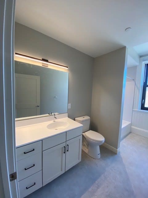 A bathroom with a sink, toilet, and mirror.
