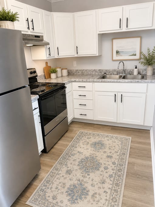 A kitchen with a refrigerator, sink, and cabinets.