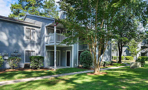 A house with a grey siding and a white porch.