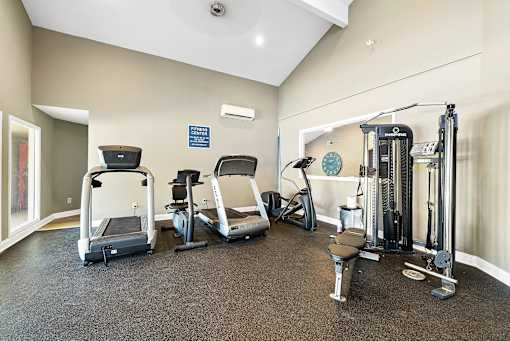 A gym with treadmills, elliptical machines, and weights.