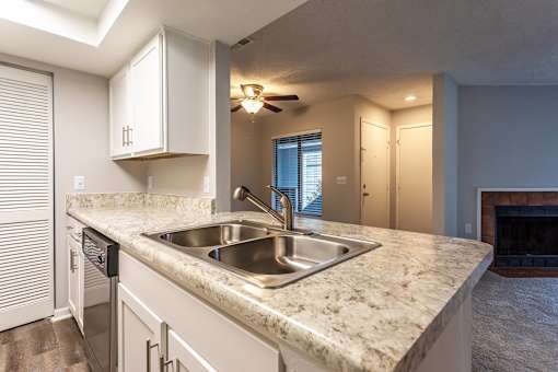 A kitchen with a marble countertop and stainless steel sink.