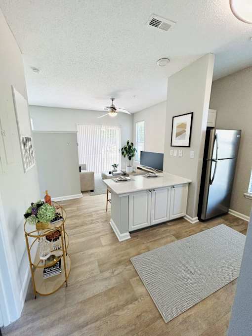 A kitchen with a refrigerator, a counter, and a plant on the counter.