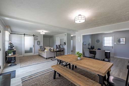 A modern open plan living and dining area with a wooden table and bench.