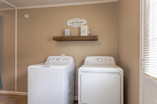 Two white front load washing machines in a laundry room.
