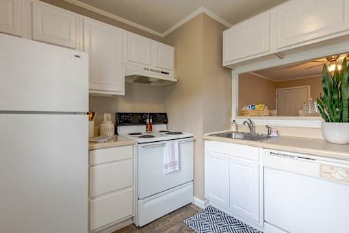 A white refrigerator is in a kitchen with white cabinets.