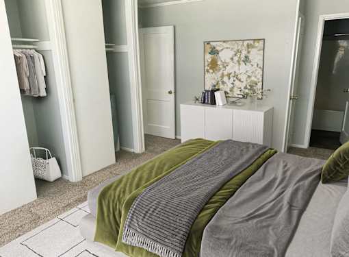 A bedroom with a bed covered in a green and grey blanket.