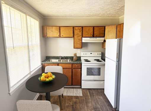 A kitchen with a table and chairs and a bowl of fruit on it.