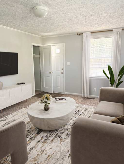 A living room with a white couch, a coffee table, and a flat screen TV.