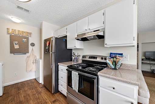 A kitchen with a stove, refrigerator, and cabinets.