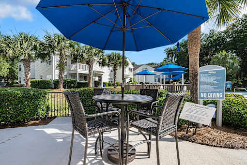 A blue umbrella is over a table with chairs around it.