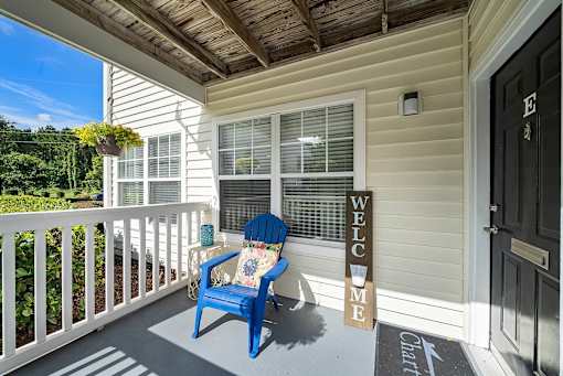 A blue chair sits on a porch with a sign that says "Welcome".