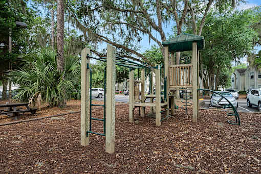 A playground with a wooden swing set and a green canopy.