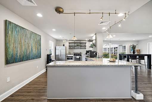 A modern kitchen with a large island and a painting on the wall.