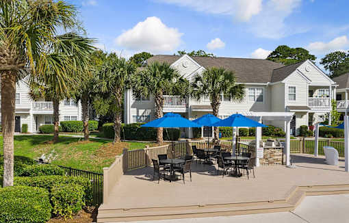 A patio with a table and chairs under a blue umbrella.