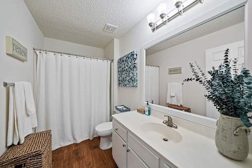 A bathroom with a white toilet, a white sink, and a white shower curtain.