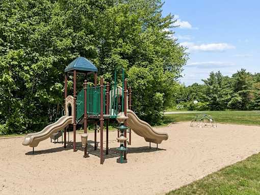 A playground with a green slide and a brown slide.