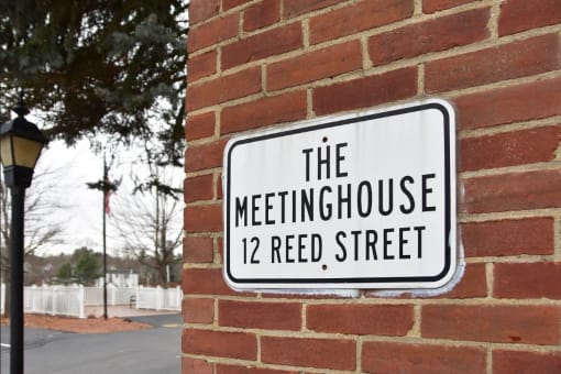 a sign for the meetinghouse 12reed street on a brick wall