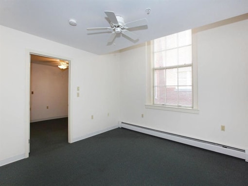 an empty room with a ceiling fan and a window