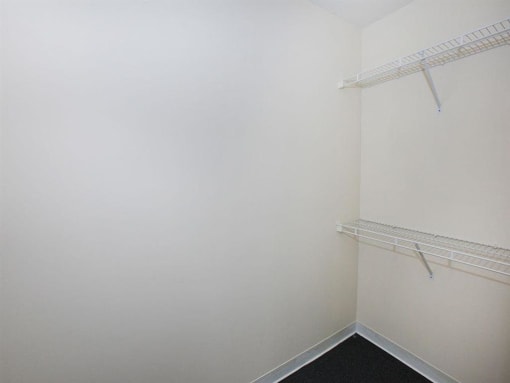 a small room with a white wall and a closet with shelves