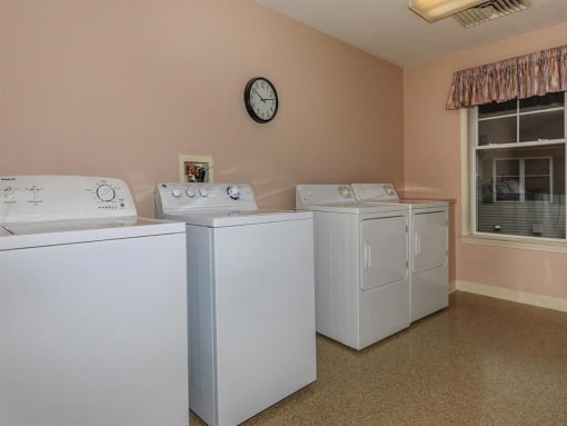 four washers and dryers in a laundry room with a clock on the wall