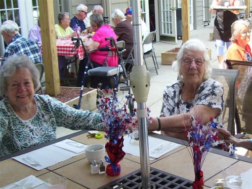 two elderly women sitting at a table with flowers