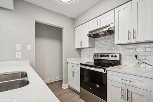 A kitchen with white cabinets and a black stove top oven.