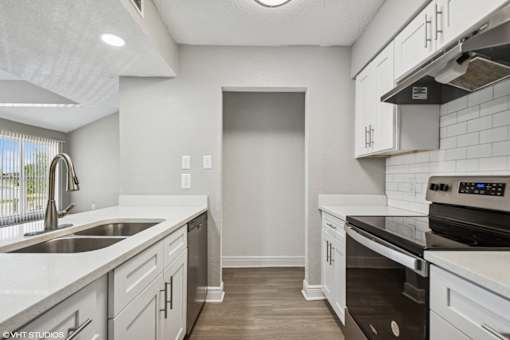 A modern kitchen with white cabinets and a black stove top oven.