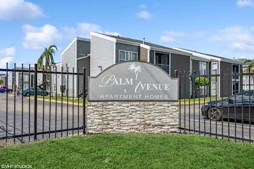 A sign that says Palm Avenue Apartment Homes in front of a building.