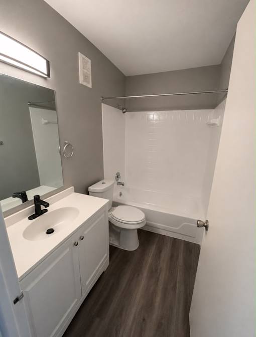 A white toilet sits in a bathroom next to a sink and mirror.