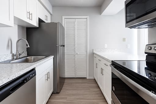A kitchen with white cabinets and black appliances.