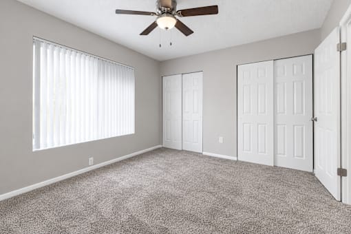 A room with a ceiling fan and carpeted floor.