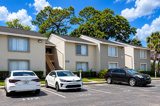 Three cars parked in a lot in front of a building.