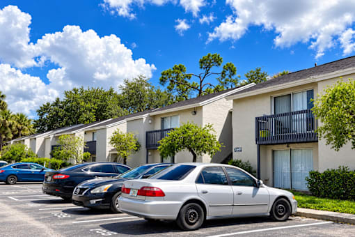 A row of cars parked in front of apartment buildings.
