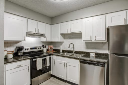 a kitchen with stainless steel appliances and white cabinets at The Highland on Briley in Nashville, TN