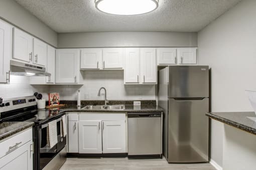 a kitchen with stainless steel appliances and white cabinets at The Highland on Briley