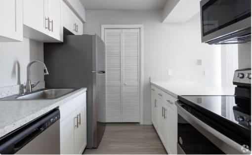 a kitchen with white cabinets and a stainless steel refrigerator at Southern Oaks Residences