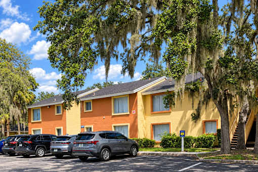 A yellow building with cars parked in front.