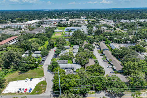 A bird's eye view of a green campus with buildings and cars.