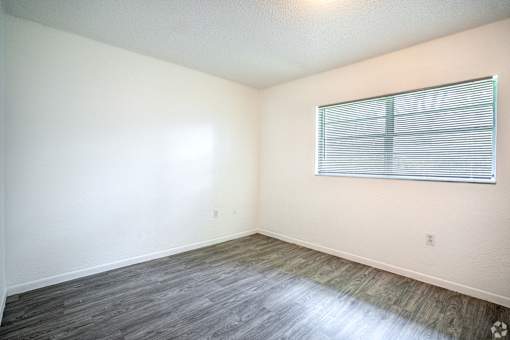 A room with a window and wooden flooring.