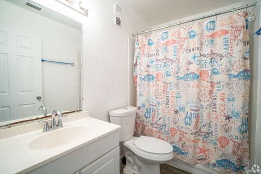 A bathroom with a shower curtain that has the words "compass" and "ocean" on it.