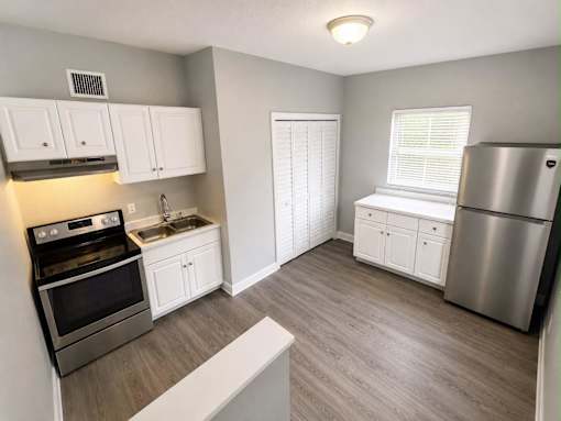 A kitchen with a stove, sink, and refrigerator.
