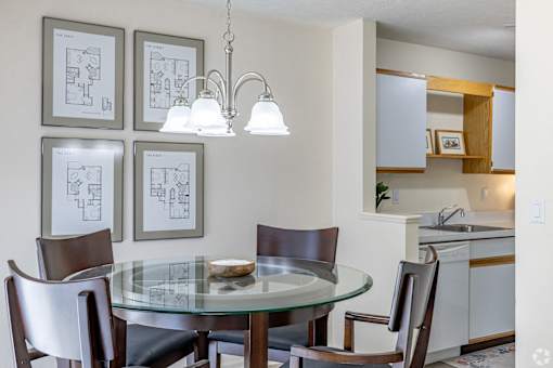 A modern dining room with a glass table and chairs.