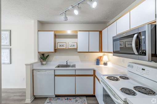 A white kitchen with wooden accents and a white stove top oven.