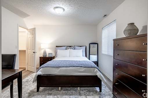 A bedroom with a bed, nightstand, and dresser.