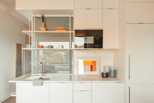a white kitchen with white cabinets and a window at Scout Living, powered by Placemakr Apartments, Georgia