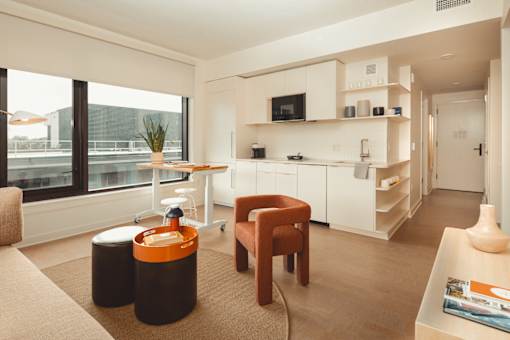 a living room with a kitchen and a large window at Scout Living, powered by Placemakr Apartments, Atlanta, GA, 30308