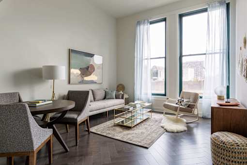A living room with a grey couch, a coffee table, and a painting on the wall at The Pennsylvanian Apartments, Pittsburgh, PA, 15222