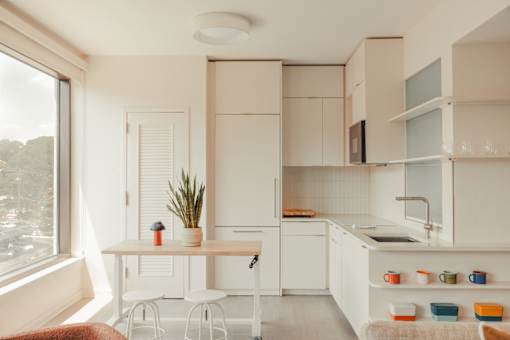 a small kitchen with white cabinets and a table and chairs at Scout Living, powered by Placemakr Apartments, Atlanta, GA, 30308