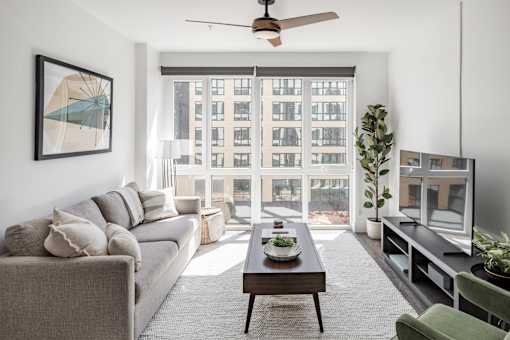 A living room with a grey couch, a coffee table, a green chair, and a painting on the wall at Anthem House Apartment , Huntsville, Alabama
