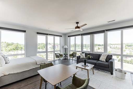 A modern bedroom with a large bed and a spacious living area with a couch and chairs at Anthem House Apartment , Huntsville, AL